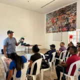 Grupo de estudiantes en un aula de clases mientras prestan atención a un instructor del SENA durante el curso de electricidad