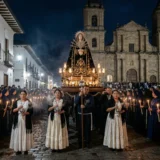 Procesión nocturna de Nuestra Señora de los Dolores en las calles empedradas de Popayán, Colombia, iluminada por cientos de velas con la Iglesia de San Agustín de fondo.