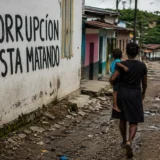 Mujer camina con niño por calle rural con mensaje sobre corrupción en Colombia