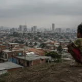 Niño observa periferia urbana bajo cielo gris