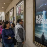 Personas observan cartel de El Día de la Revelación en cine urbano