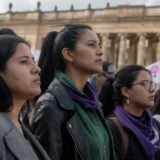 Mujeres observan manifestación política frente a edificio institucional en Colombia