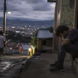 Hombre sentado en una calle urbana durante la noche en un barrio latinoamericano