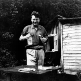 Malcolm Lowry sostiene una botella junto a su casa en Canadá