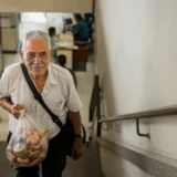 Adulto mayor vende rosquillas mientras sube escaleras de una oficina en Cali