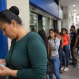 Mujer cuenta dinero frente a una entidad financiera en Colombia