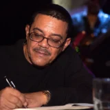 Jairo Varela escribiendo durante una jornada musical en un ambiente de salsa