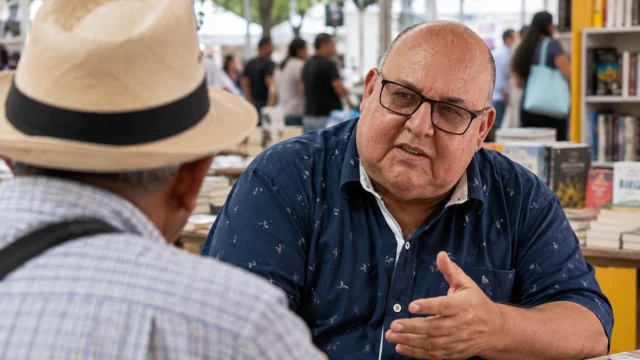 Fernando Alexis conversa con un hombre de espaldas durante una recreación de la Feria del Libro de Cali