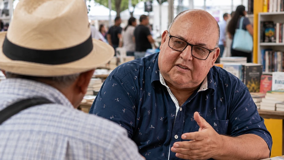 Fernando Alexis conversa con un hombre de espaldas durante una recreación de la Feria del Libro de Cali